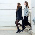 Two young businesswoman walking on the street near office buildi