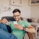 Happy young man shopping online at home