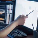 Analyzing data. Close-up of young businessman pointing on the data presented in the chart with pen while working in creative office