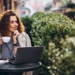 young-businesswoman-working-computer-outside-cafe-1-scaled