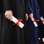 Close up of university students graduates in mantles holding diplomas over white background.
