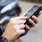 Beautiful young woman using her mobile phone in the street.